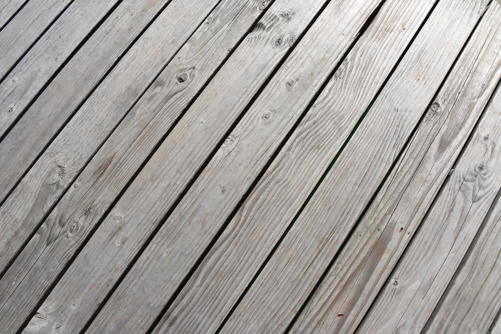 Planches de bois grises posées en diagonale sur un sol extérieur Planches de bois grises posées en diagonale sur un sol extérieur