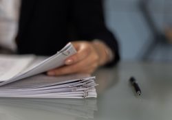 Main tenant classeur de documents sur table, stylo à côté